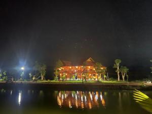 duży budynek z oświetleniem na wodzie w nocy w obiekcie Dak Nguyen Homestay & Farm 2 w mieście Gia Nghĩa