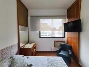 1 dormitorio con 1 cama, 1 silla y 1 ventana en Volpi Residence na Savassi - Sinta-se em casa!, en Belo Horizonte