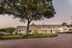 ein großes weißes Haus mit einem Baum in der Einfahrt in der Unterkunft Protea Hotel by Marriott Chingola in Chingola