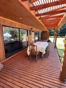 una terraza de madera con mesa y sillas. en Fabulosa casa en parcela Molco Alto, en Molco