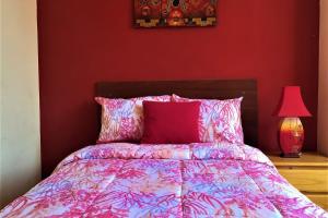 1 cama con edredón rosa y pared roja en Hostal Rodinn, en Nazca