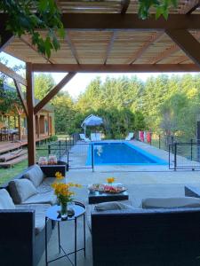 un patio con sofá y mesas frente a la piscina en Fabulosa casa en parcela Molco Alto, en Molco