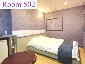 Hotel NewMie (Adult Only) في طوكيو: غرفة نوم صغيرة مع سرير وطاولة