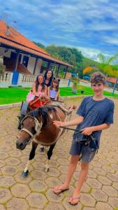 een jongen die naast een paard staat met drie meisjes bij Pousada temática Estrada Real in Caxambu