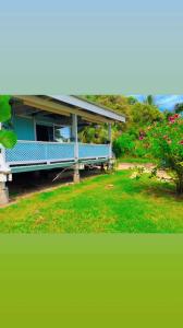 a blue bench in front of a house with flowers at Haranai Camping & Tours in Te-Fare-Arii