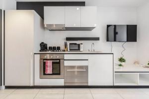 uma cozinha branca com um fogão e um micro-ondas em Central & Stylish in St Kilda w AC, WiFi & Balcony em Melbourne