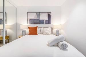 um quarto branco com uma grande cama branca com almofadas em Central & Stylish in St Kilda w AC, WiFi & Balcony em Melbourne