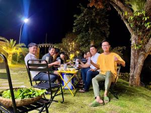 grupa ludzi siedzących w nocy przy stole w obiekcie Dak Nguyen Homestay & Farm 3 w mieście Gia Nghĩa