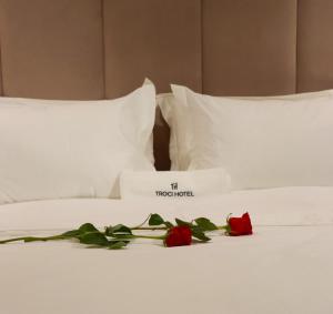 a white bed with two roses on it at Troci Hotel in Tirana