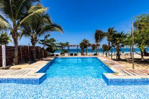 a swimming pool with palm trees and the beach at Mamaqocha in Canoas de Punta Sal
