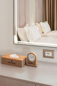 a clock on a table in front of a mirror at Troci Hotel in Tirana