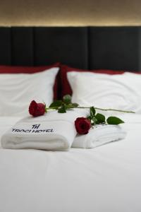 two towels with roses on top of a bed at Troci Hotel in Tirana