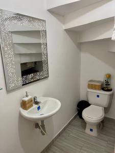 W łazience znajduje się umywalka, toaleta i lustro. w obiekcie Hermosa casa w mieście Cúcuta