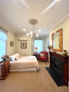 a bedroom with a bed and a mirror and a fireplace at Porters Cottage Garden in Albury