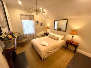 una camera da letto con un letto e uno specchio sul muro di Porters Cottage Garden ad Albury