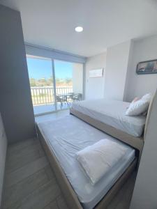 a small bedroom with two beds and a balcony at Departamento al pie del mar - Punta Blanca in Punta Blanca