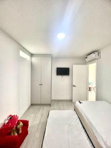 a white room with a bed and a tv at Departamento al pie del mar - Punta Blanca in Punta Blanca