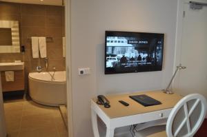 ein Badezimmer mit einem Fernseher an der Wand und einem Schreibtisch mit Laptop in der Unterkunft Romantik Parkhotel het Gulpdal in Slenaken