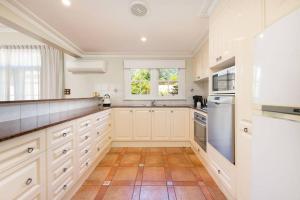 a large kitchen with white cabinets and a window at Porters Cottage Classic in Albury