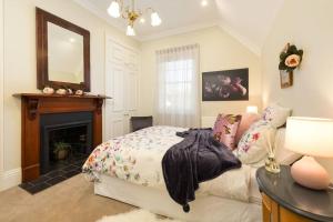 a bedroom with a bed and a fireplace and a mirror at Porters Cottage Classic in Albury
