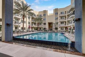 una piscina en el patio de un edificio de apartamentos con palmeras en Paradise Cozysuites Under the Palms w jacuzzi 20 en Phoenix