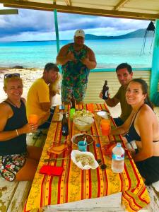 a group of people sitting around a table on the beach at Haranai Camping & Tours in Te-Fare-Arii
