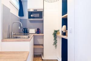 una cucina con armadi bianchi e pareti blu di Equipped studio in the center of Lille a Lille Altre 9 foto