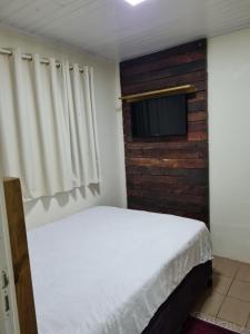 - une chambre avec un lit et une télévision à écran plat dans l'établissement Kitnet em Torres, à Torres