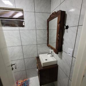 La salle de bains est pourvue d'un lavabo et d'un miroir. dans l'établissement Kitnet em Torres, à Torres