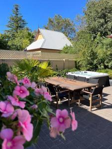 a picnic table in a backyard with pink flowers at Porters Cottage Oasis in Albury