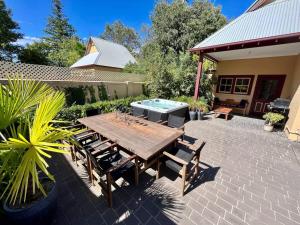 a patio with a wooden table and chairs and a pool at Porters Cottage Oasis in Albury