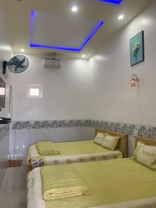2 camas en una habitación con TV en la pared en Nhà nghỉ Bá Thành - Lý Sơn, en Quảng Ngãi