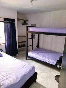 two bunk beds in a room with purple sheets at Casa familiar cerca a la estación del metro in Medellín