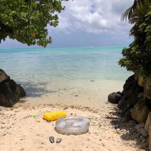 a yellow frisbee and flip flops on a beach at FARE Tatahi in Parea