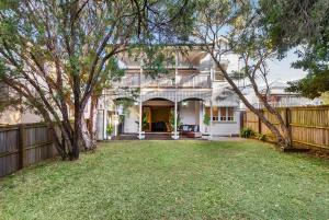 a white house with a fence and a yard at Heritage Queenslander Gem - Families & Groups - Minutes to CBD & South Brisbane in Brisbane