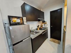 a small kitchen with a sink and a refrigerator at One-Bedroom and Studio Apartment near SM City , IT Park and Ayala Mall - NO PARKING at Bamboo Bay Community in Mandaue City