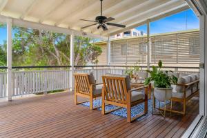 um alpendre com uma mesa e cadeiras e uma ventoinha de tecto em Unique Character Queenslander Home! Just Minutes to CBD & South Brisbane em Brisbane