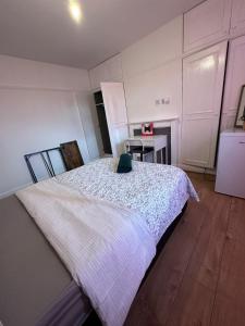 a bedroom with a white bed with a green hat on it at Esther's Peaceful Oasis in Erith