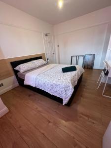 a bedroom with a bed and a wooden floor at Esther's Peaceful Oasis in Erith