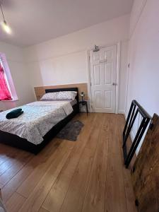 a bedroom with a bed and a wooden floor at Esther's Peaceful Oasis in Erith