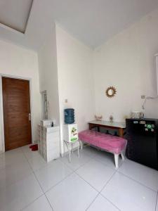 Mahardika Homestay Gamping في سليمان: غرفة معيشة مع طاولة ومقعد وردي +5 صور