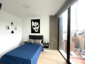 een slaapkamer met een blauw bed en een groot raam bij Five Stars Suites - Gótica - iQON Quito in Quito