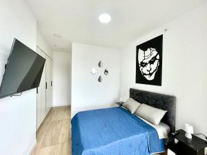 een slaapkamer met een blauw bed en een flatscreen-tv bij Five Stars Suites - Gótica - iQON Quito in Quito