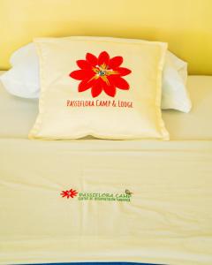 Una cama con una almohada con una flor roja. en Passiflora Camp, en Puerto Maldonado