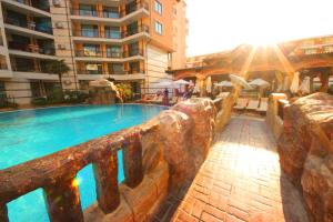 una piscina junto a un edificio con luz solar en Menada Apartments in Karolina, en Sunny Beach