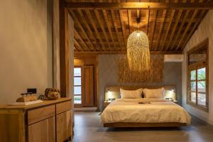 een slaapkamer met een groot bed en een kroonluchter bij Villa Lawas - Private Retreat in Gawok
