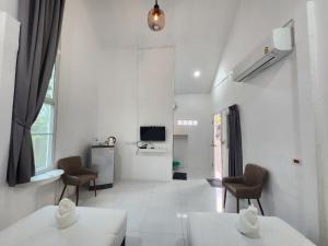 a white living room with two tables and chairs at คุณเก้า รีสอร์ท in Non Sa-at