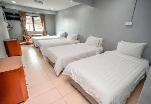drie bedden in een kamer met witte lakens bij LABIS SUNRISE FARM STAY in Labis