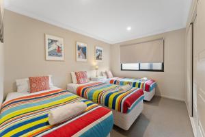 a room with two beds and a couch in it at Khione 1 Modern spacious with views towards Lake Jindabyne the mountains beyond in Jindabyne