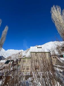 Gondla的住宿－SNOWFLAKE Homestay，一座被雪覆盖的建筑,背景是一座山
